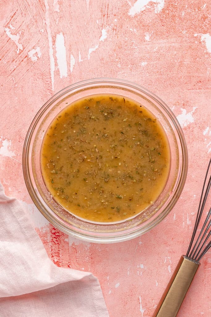 Prepared vinaigrette after whisking, smooth and emulsified, in a small glass bowl.