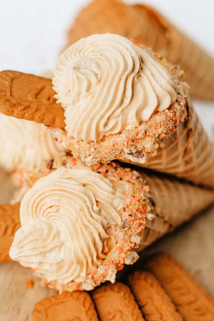 Two finished pumpkin cheesecake cones with piped filling and Biscoff cookies on top