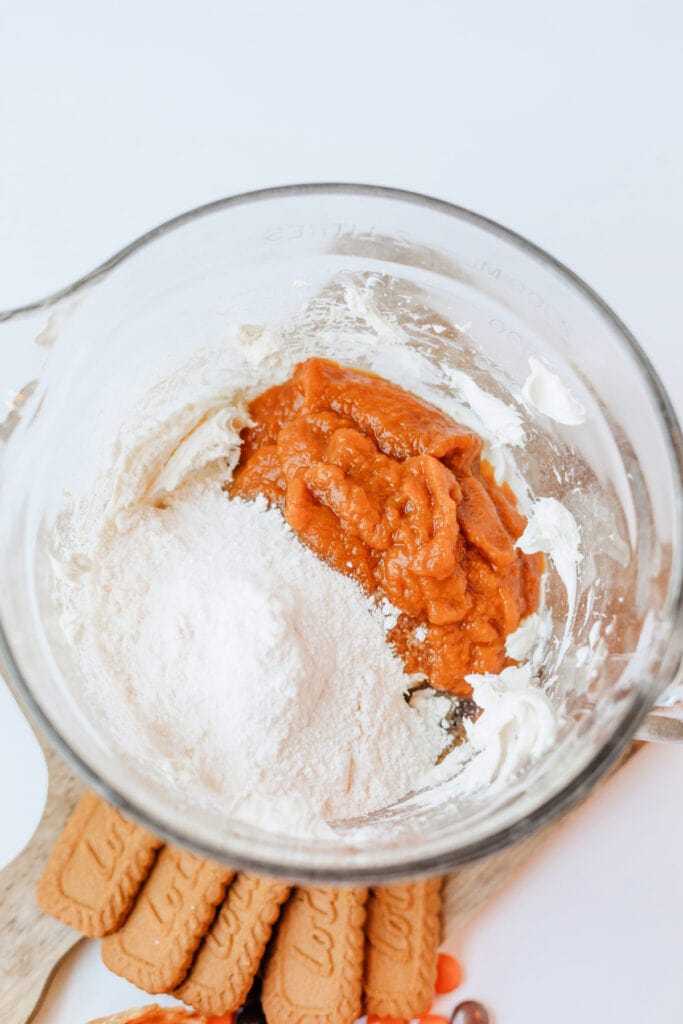 Pumpkin pie mix and cheesecake pudding mix added to whipped cream cheese in a bowl
