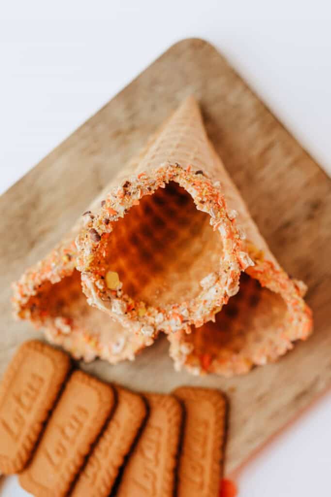 Close-up of waffle cones with rims coated in crushed Reese’s Pieces