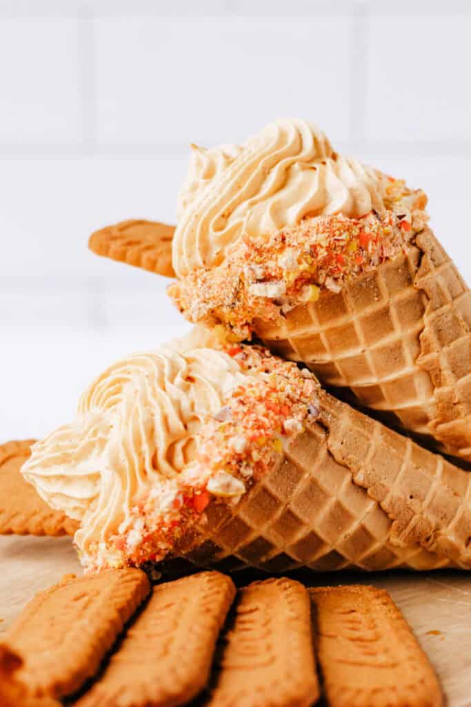 Two finished pumpkin cheesecake cones with piped filling and Biscoff cookies on top