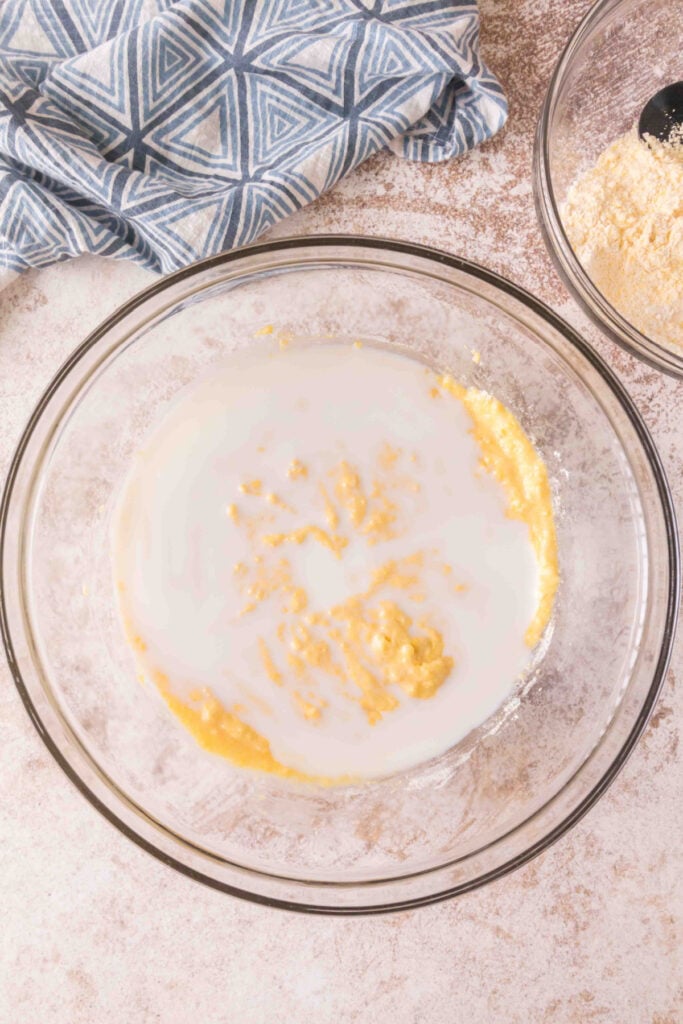 Mixing bowl with wet cornbread batter after milk is poured in, ready to be combined.