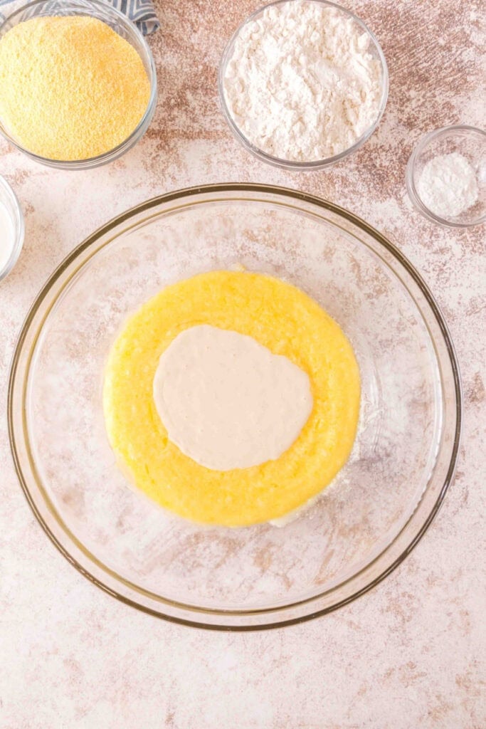 Sourdough discard starter added to the wet mixture of butter, sugar, and eggs in a glass bowl.