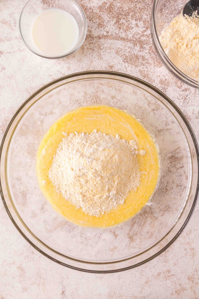 Batter partially mixed with flour and cornmeal sitting on top, before adding milk.