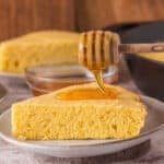 Square crop of cornbread slice on a plate with honey dipper, styled for Pinterest or Instagram.