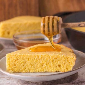 Square crop of cornbread slice on a plate with honey dipper, styled for Pinterest or Instagram.
