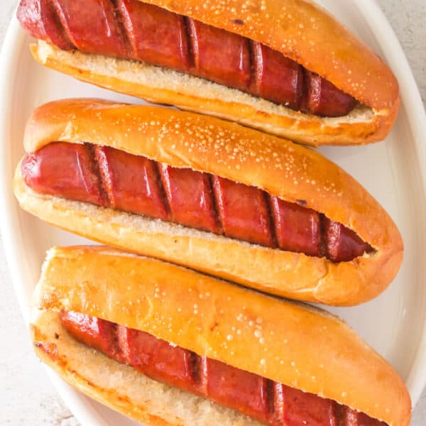 Square-cropped image of hot dogs in toasted buns ready to serve