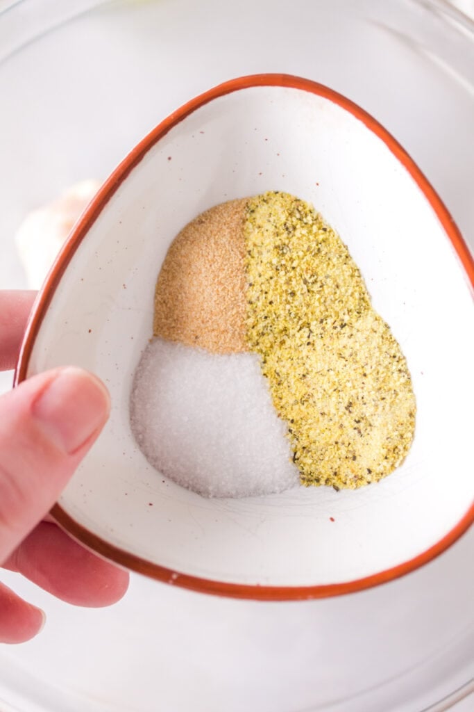 Close-up of a small bowl holding lemon pepper, garlic powder, and salt seasoning.