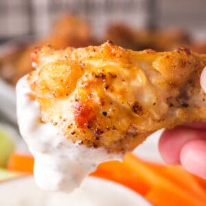 Crispy air fryer lemon pepper chicken wing being dipped into creamy ranch dressing.