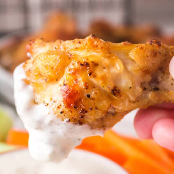 Crispy air fryer lemon pepper chicken wing being dipped into creamy ranch dressing.