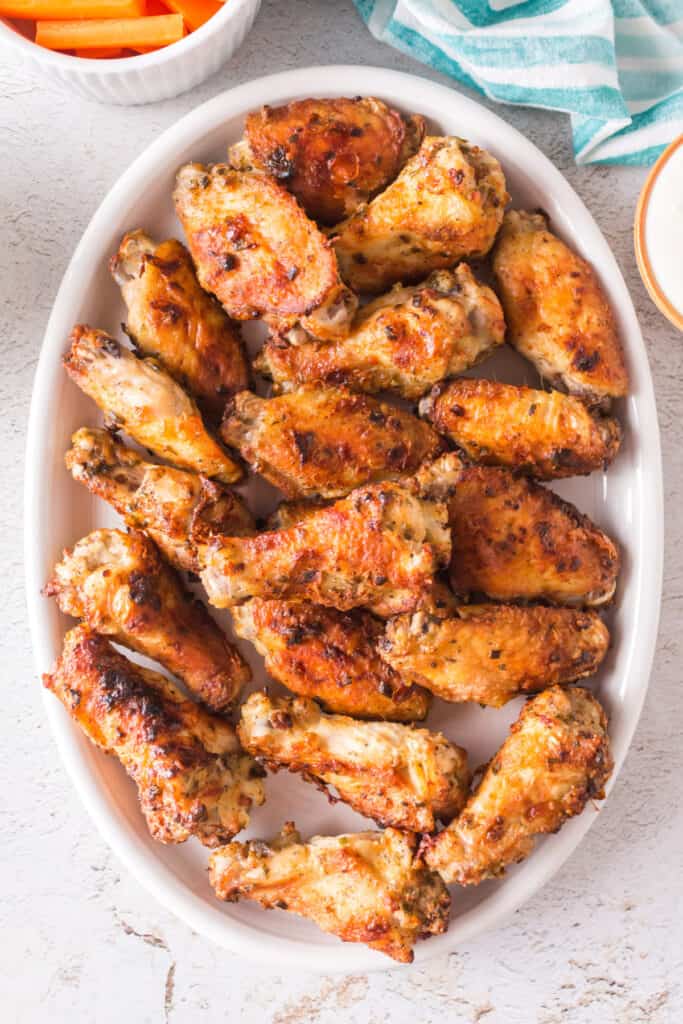 Platter of crispy golden ranch chicken wings served with carrot sticks and dipping sauce