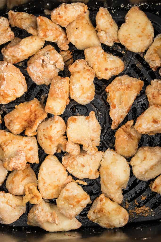 Crispy golden chicken pieces in the air fryer basket after cooking, showing a crunchy texture.