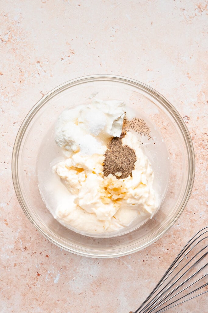 Bowl of mayonnaise, Greek yogurt, vinegar, minced garlic, sugar, salt, and black pepper before whisking into shwarma white sauce.