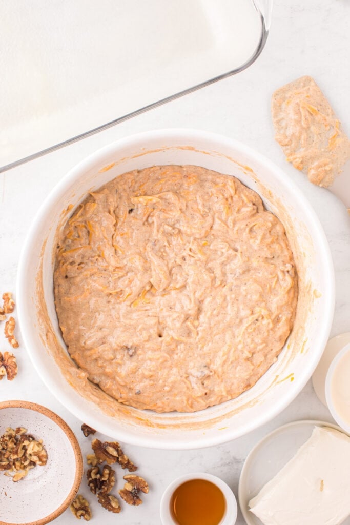 Bowl of butternut squash cake batter with walnuts mixed in, ready to be poured into the baking dish.
