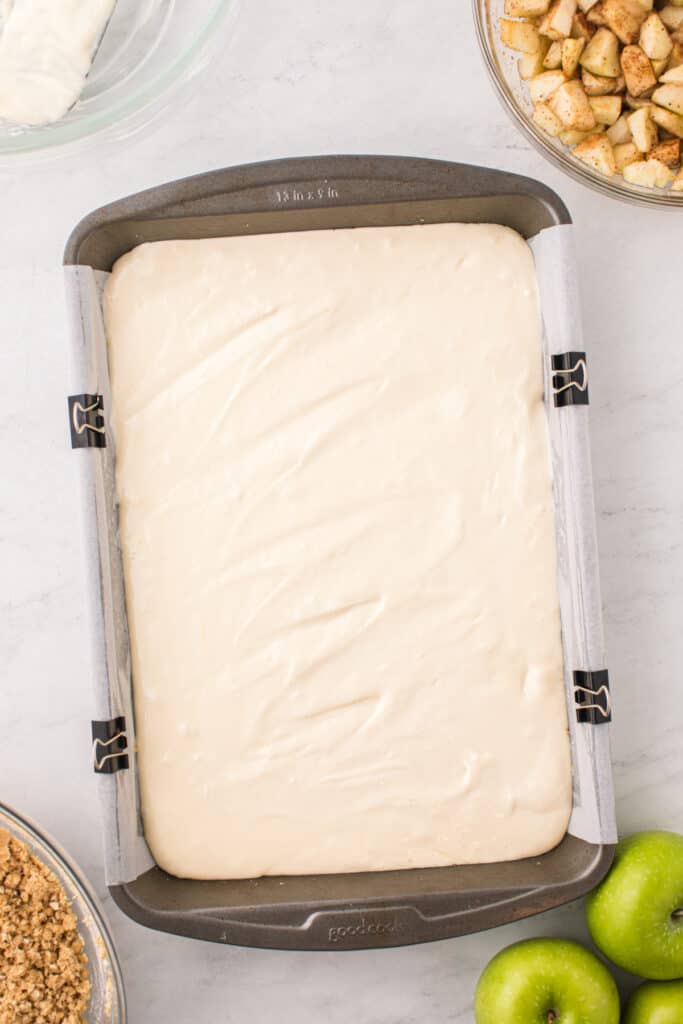 Cheesecake layer spread evenly over graham cracker crust in a 9x13-inch pan.