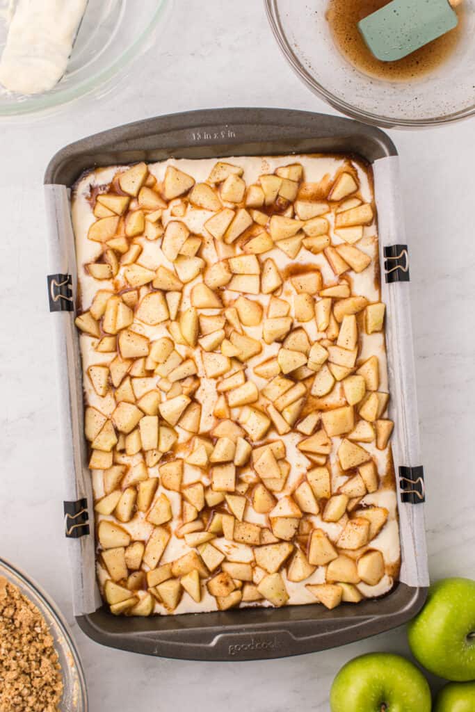 Spiced apple mixture layered evenly over cheesecake filling in the pan.