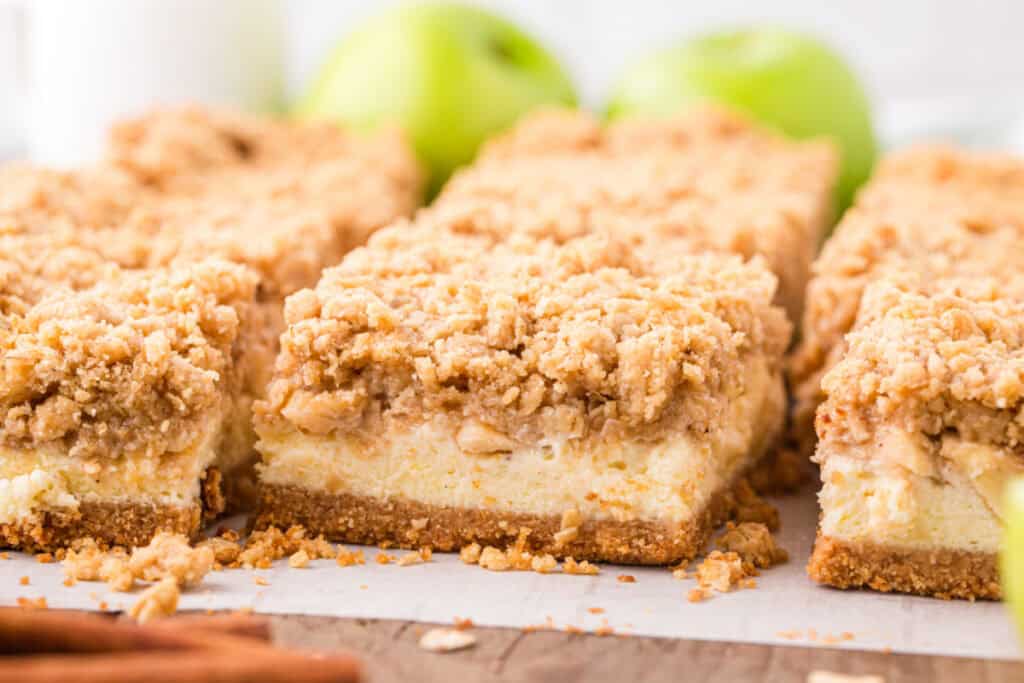 Close-up of sliced caramel apple cheesecake bars showing creamy cheesecake and crumb topping.