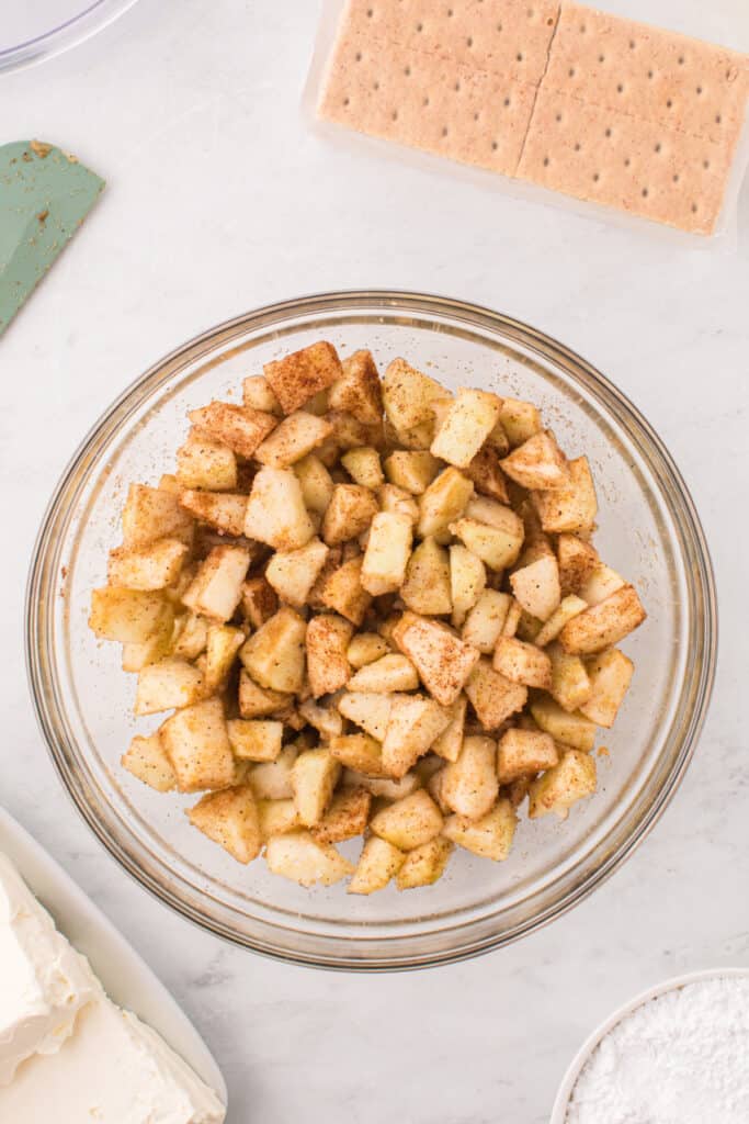 Mixed apple filling in a glass bowl coated with sugar and spices.