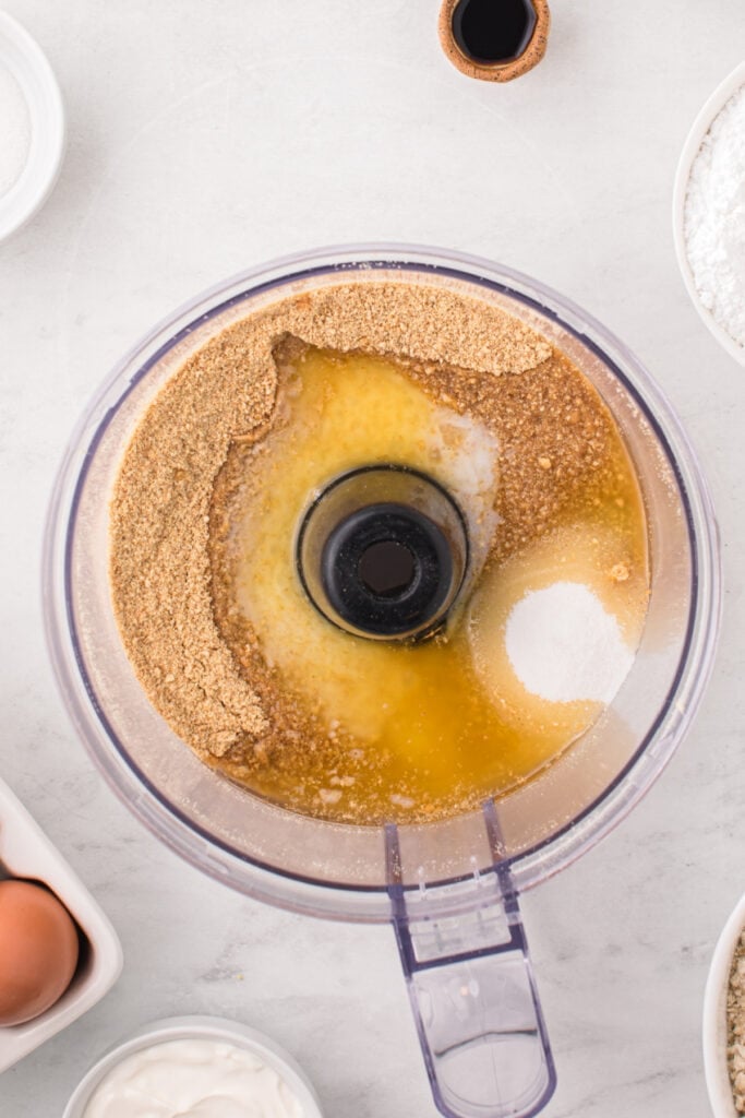 Food processor filled with graham cracker crumbs, sugar, and melted butter.