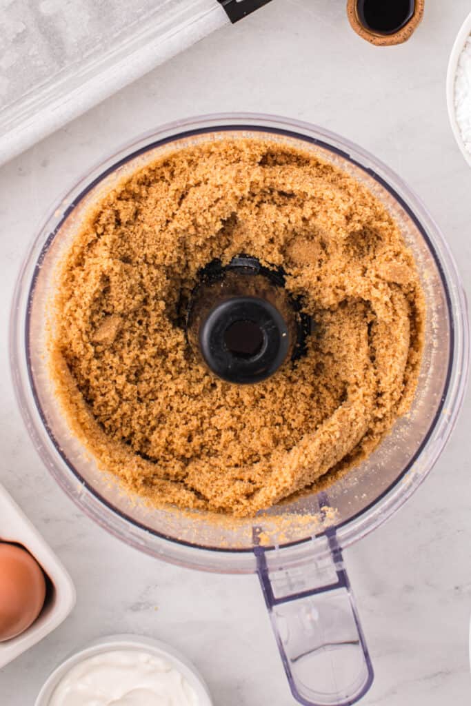 Crumbly graham cracker crust mixture in a food processor after pulsing.
