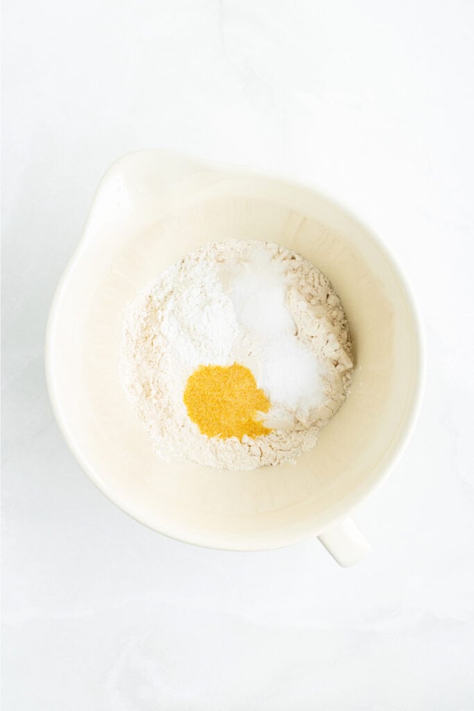 Mixing bowl with flour, baking powder, sugar, salt, and garlic powder ready to be whisked together.