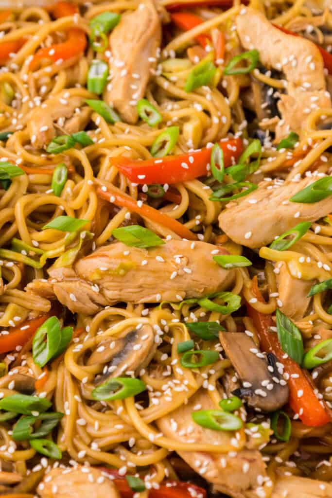 Close-up of Chicken Lo Mein with chicken, noodles, mushrooms, peppers, and sesame seeds