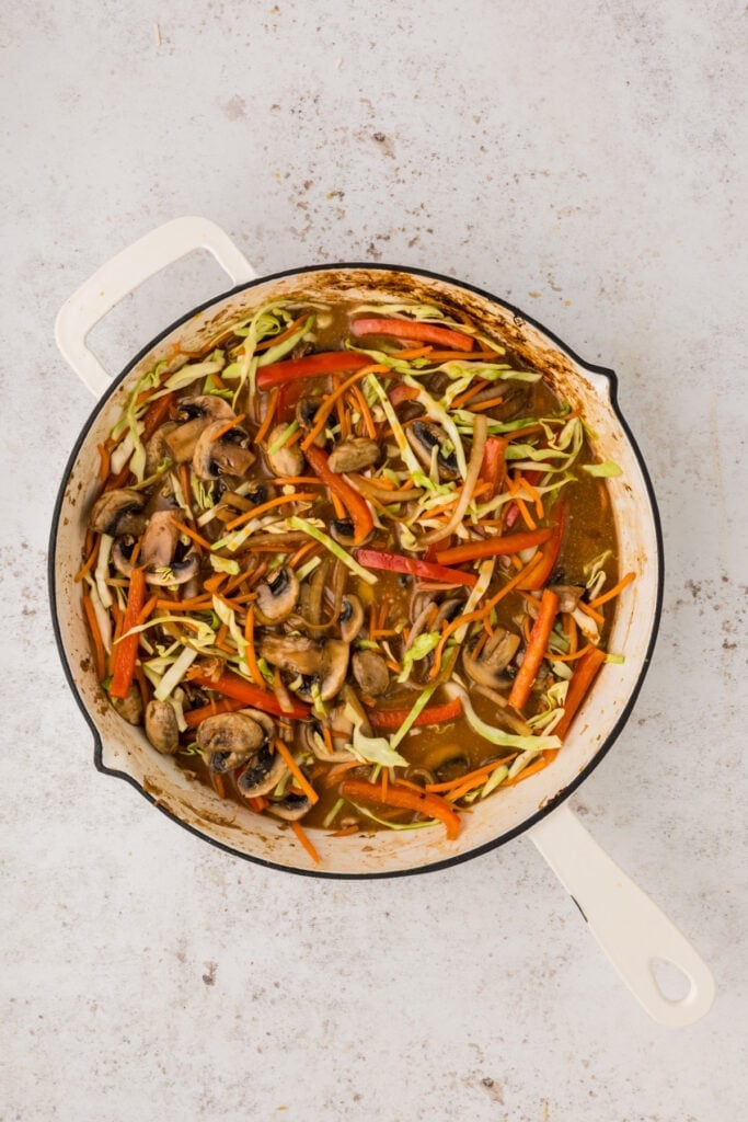 Vegetables in a skillet with chicken broth and sauce added