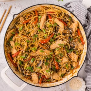 Square overhead image of Chicken Lo Mein in skillet topped with sesame seeds and green onions