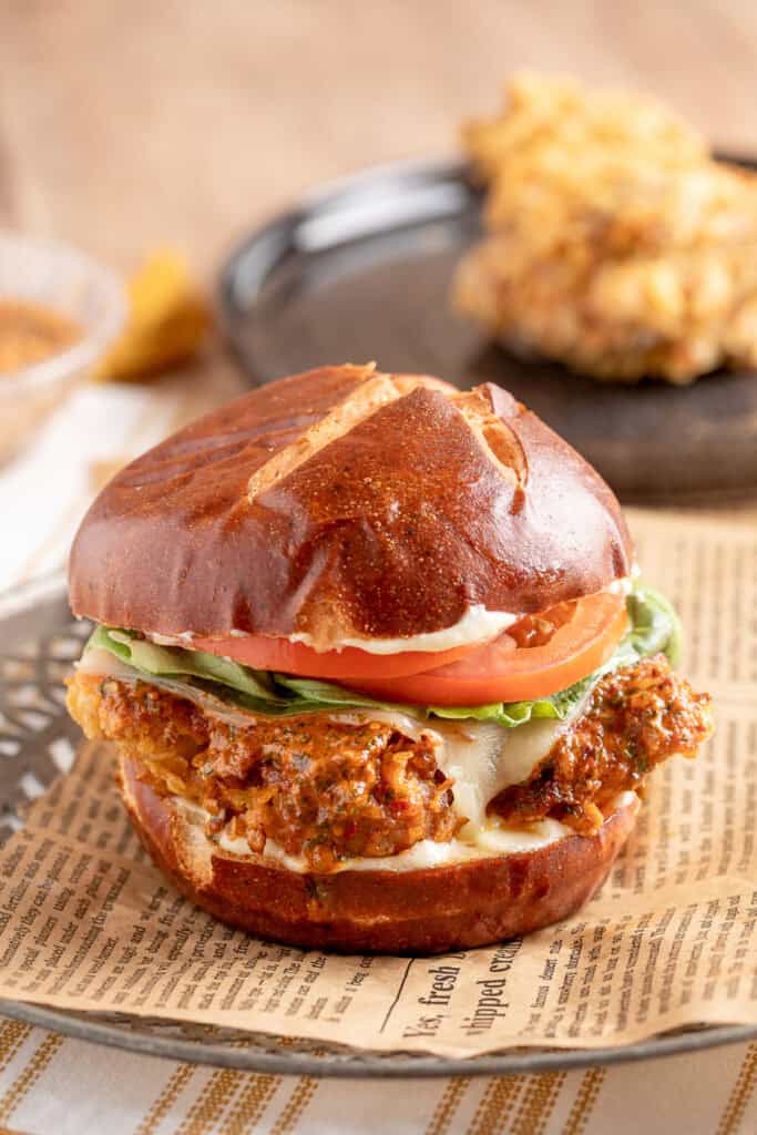 Close-up of a Cowboy Butter Crispy Chicken Sandwich on a pretzel bun with lettuce, tomato, and melted cheese.