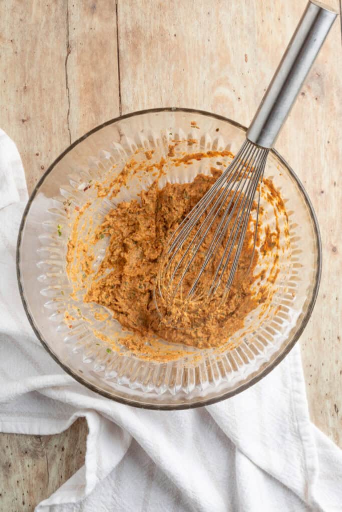 Bowl of freshly whisked cowboy butter sauce with herbs and spices blended into a thick, flavorful spread.