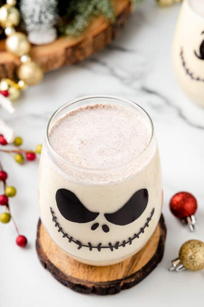 Overhead shot of a single Jack Skellington Cocktail in a decorated glass, surrounded by ornaments and greenery.
