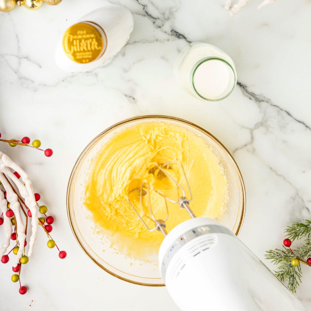 Bowl of egg yolk and sugar mixture whipped into a fluffy, pale yellow consistency with a hand mixer.
