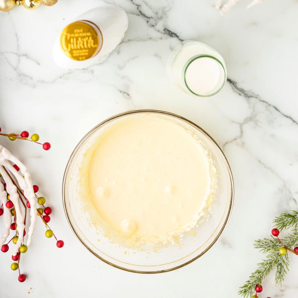 Lightened egg yolk mixture smoothed into a frothy batter in a glass bowl.