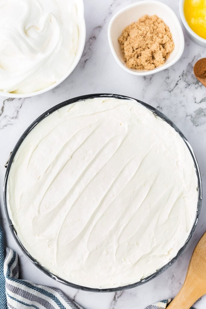 RumChata cheesecake layer smoothed over the chilled pumpkin layer in the springform pan, creating two distinct layers.