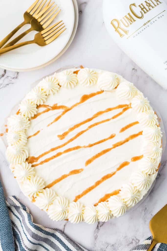 Overhead view of the finished no bake RumChata pumpkin cheesecake topped with piped whipped cream swirls and cinnamon drizzle.