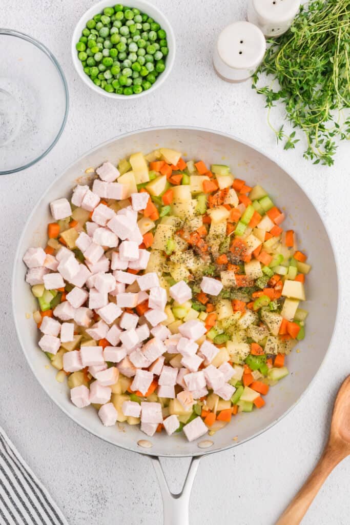 Diced turkey and dried herbs added to skillet of sautéed vegetables for the pot pie filling.