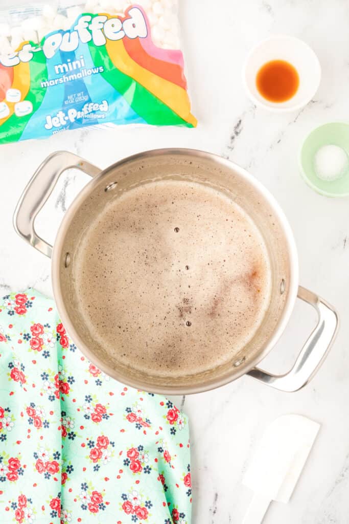 Browned butter foaming and turning golden in a stainless steel pot with vanilla and salt nearby.
