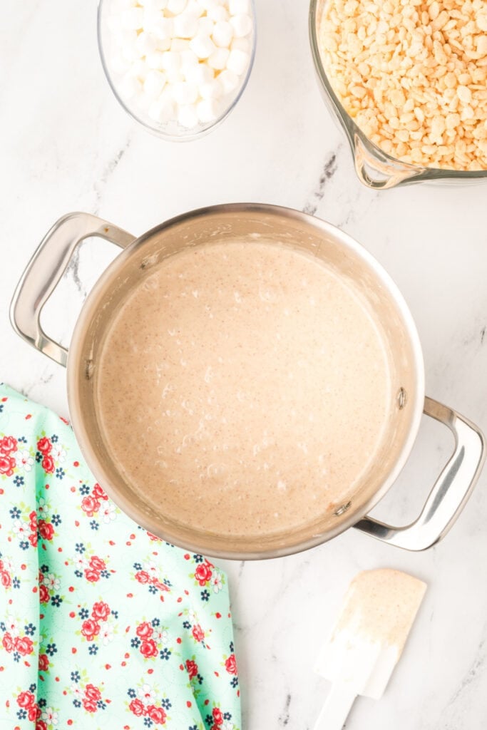 Melted marshmallow mixture combined with browned butter in a pot, ready for crispy rice cereal to be stirred in.