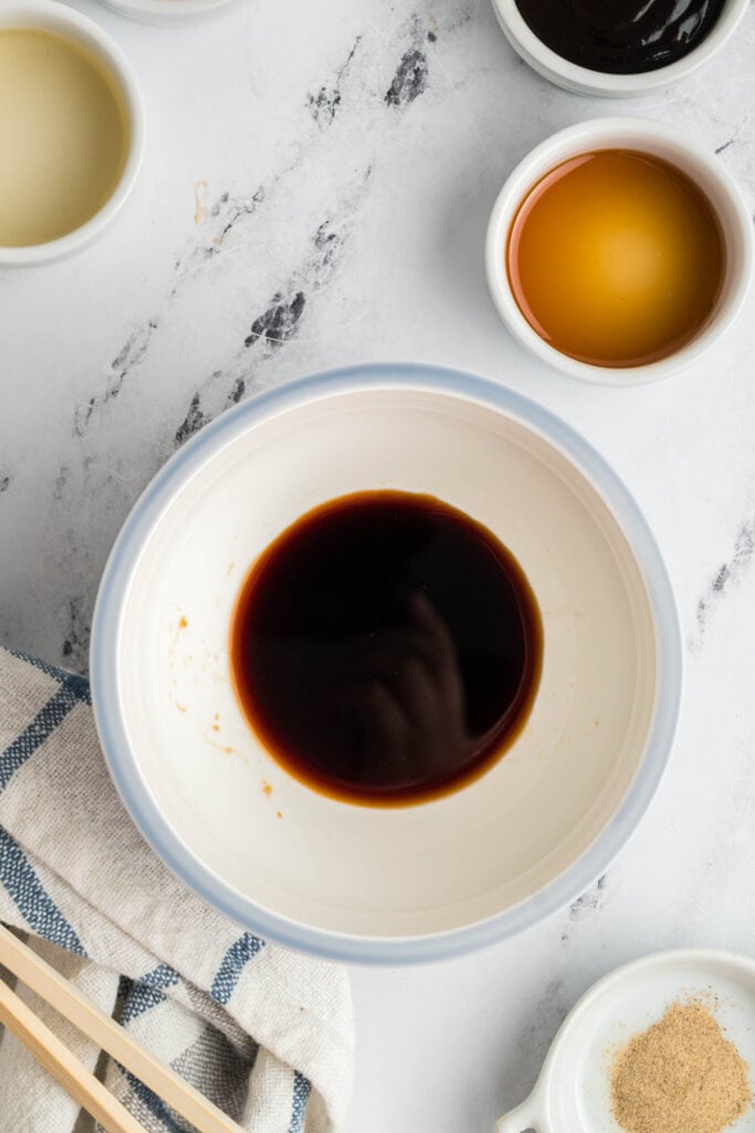 Small bowl of soy sauce mixture starting the lo mein sauce with other ingredients nearby.
