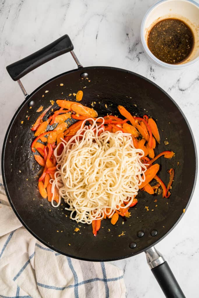 Cooked lo mein noodles added to the wok with the sautéed vegetables.