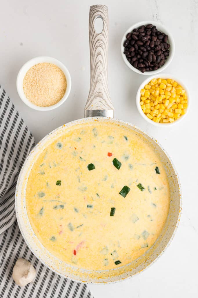 Creamy pepper sauce simmering, parmesan, beans, and corn set aside.