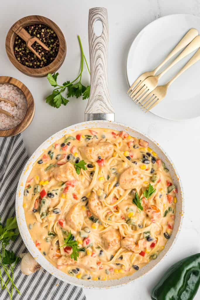 Finished southwest chicken fettuccine alfredo in the skillet, garnished with parsley.