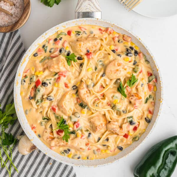 Overhead square crop of skillet filled with southwest chicken fettuccine alfredo, garnished with parsley.