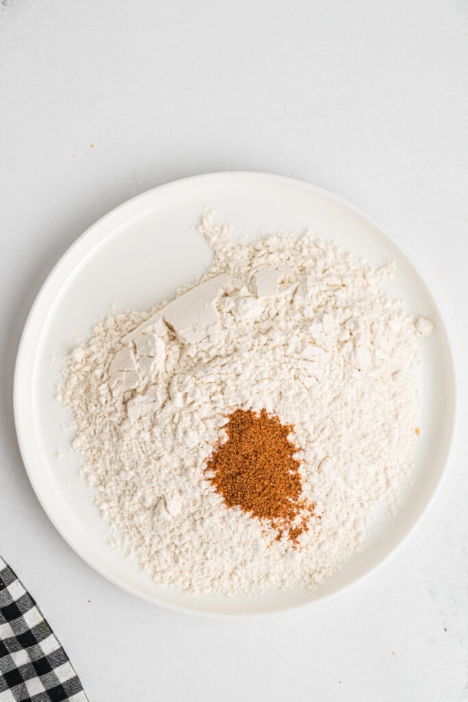 Plate of flour with ancho chili powder mixed in for dredging chicken tenders.
