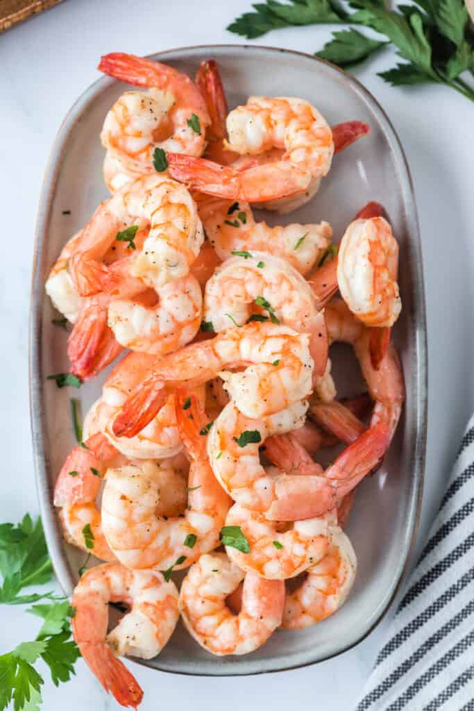 Close-up of air-fried shrimp on a gray platter, garnished with fresh parsley.