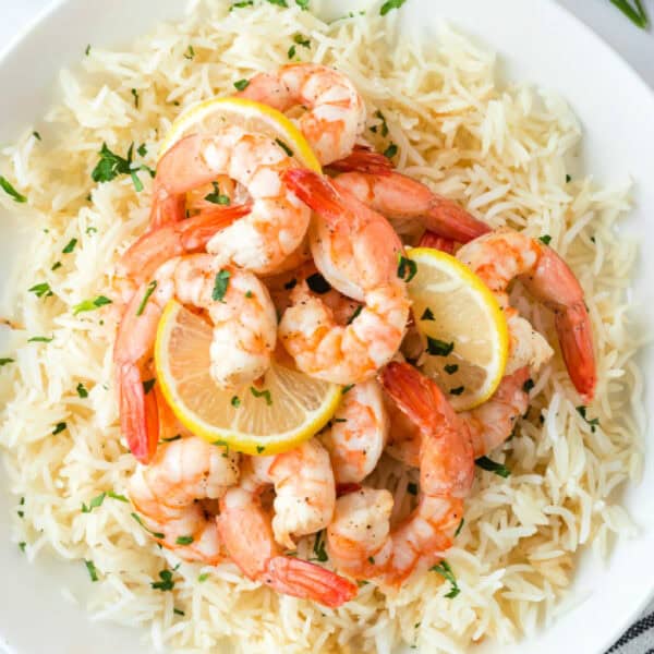 Square crop of Air Fryer Shrimp with lemon slices served over rice.