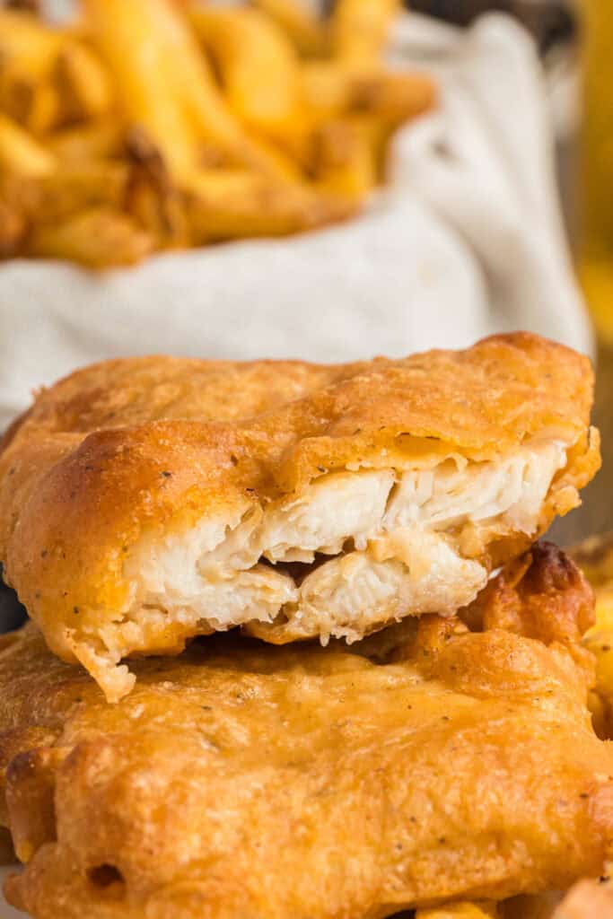 Close-up of flaky beer battered fish showing the crisp coating and tender white fish inside.