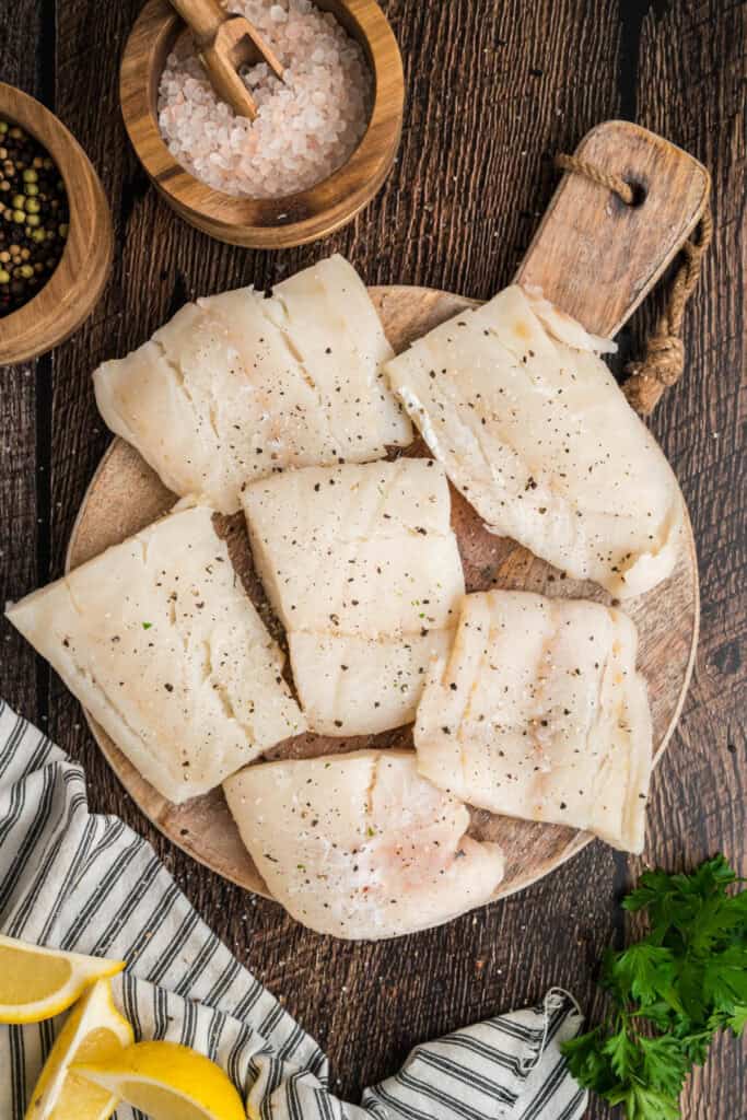 Cod filets seasoned with salt and black pepper, ready for battering and frying.