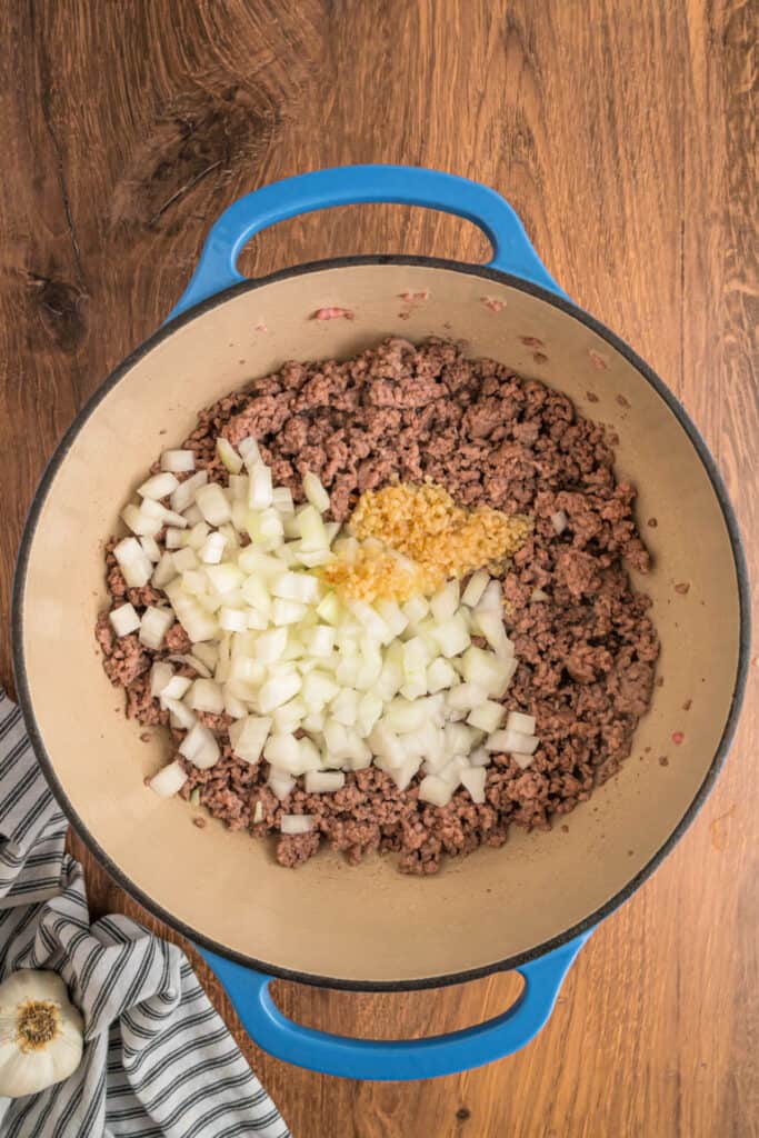 Chopped onions and minced garlic added to the browned meat in the dutch oven.