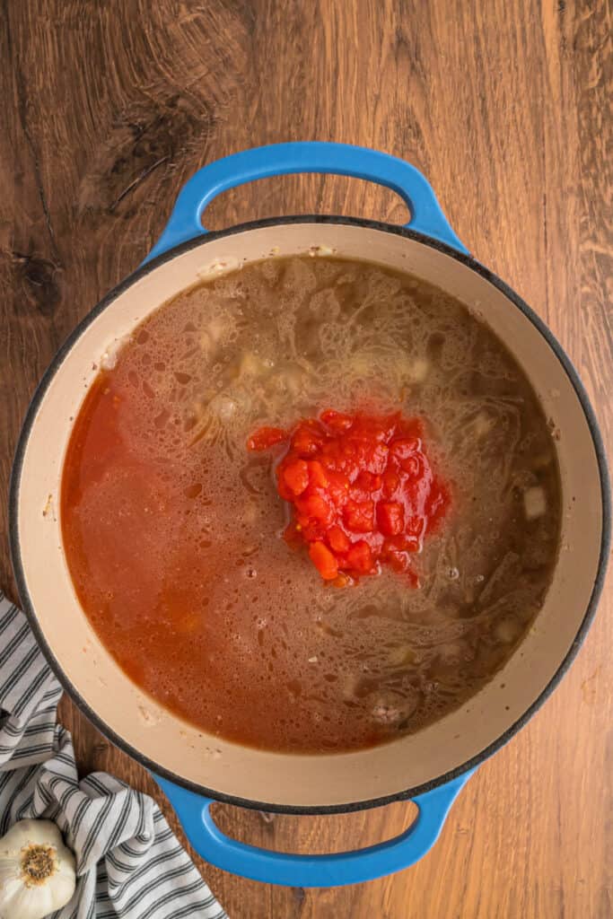 Beef broth, V8 juice, and diced tomatoes added to the meat mixture in the pot.